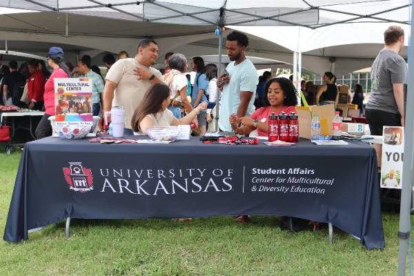 People behind a table and booth at the University of Arkansas